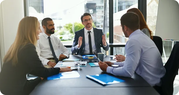 A group of diverse business professionals engaged in discussion around a conference table