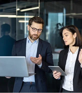 Two business professionals discussing strategy in front of a laptop in a modern office